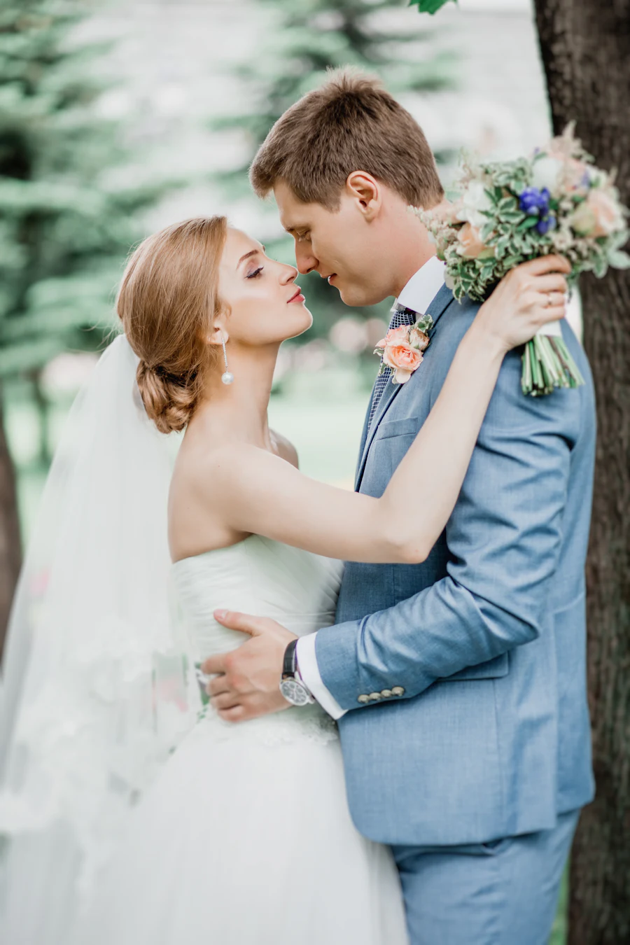 Los novios a punto de besarse entre los árboles